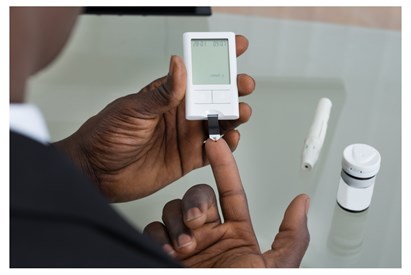 Person using an at-home finger prick blood glucose monitor
