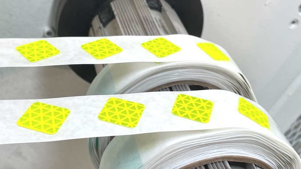 Rolls of pressure-sensitive adhesive labels on a die-cutting press spindle.