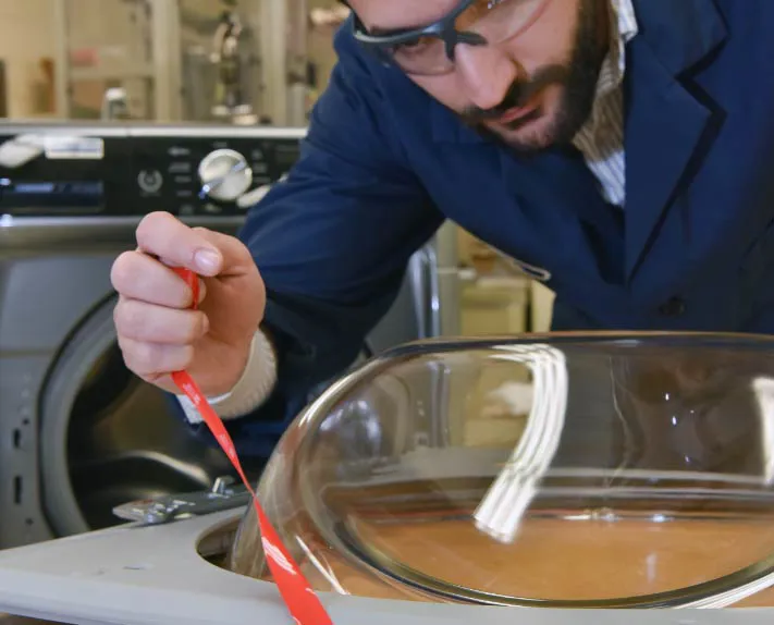 Man with safety glasses removing tape from surface